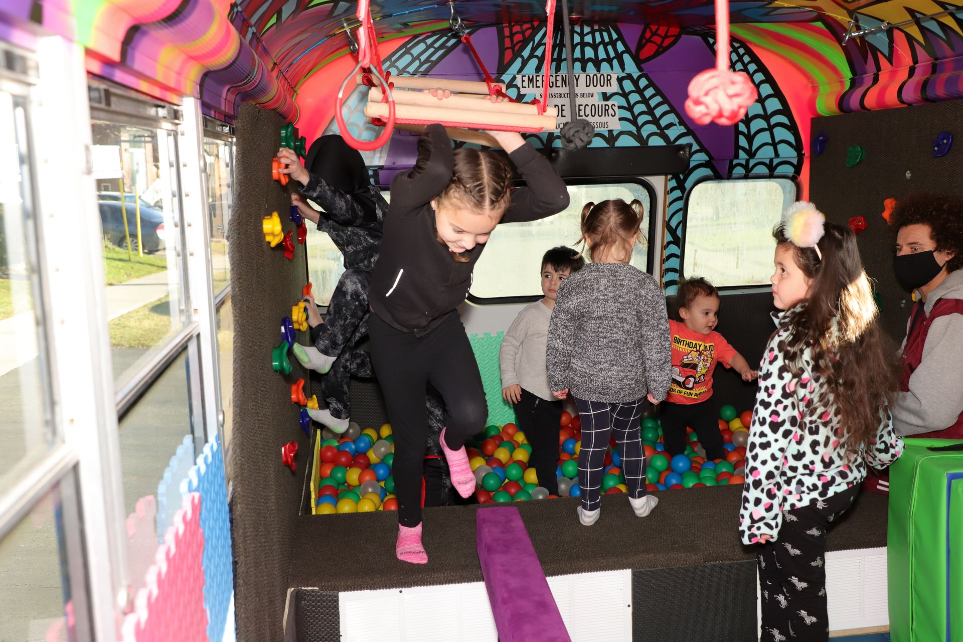 Kids mid-tumble beside the bus, bright daylight